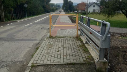 żółta bariera stojąca na chodniku przy drodze powiatowej w Kobylance
