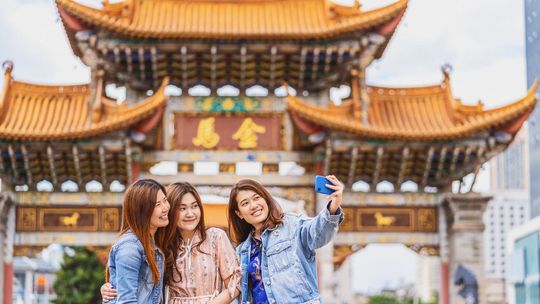 trzy kobiety robią sobie selfie telefonem, w tle zabudowania w chinach