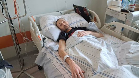 zdjęcie przedstawia osobę leżącą w szpitalnym łóżku