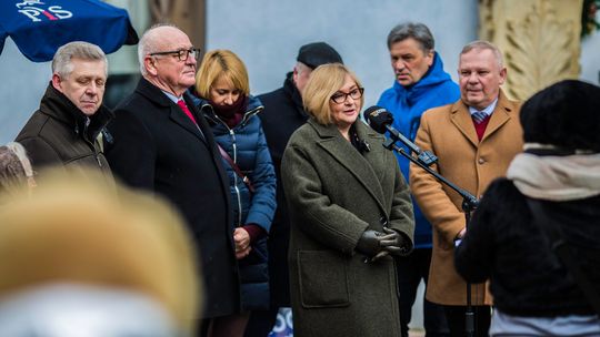 zdjęcie przedstawia kilka osób stojących na ulicy, mówiących do mikrofonu