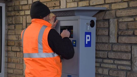 Kierowcy, dobra wiadomość. Parkowanie w Gorlicach za darmo Zdjęcie przedstawia parkometr i pracownika