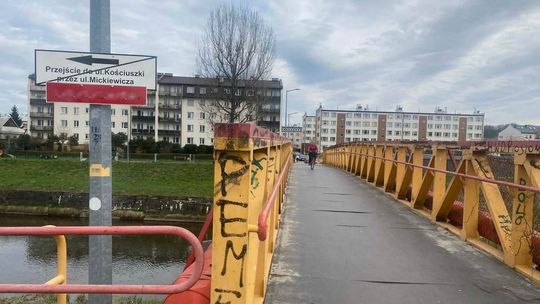 zdjęcie przedstawia ludzi idących mostkiem