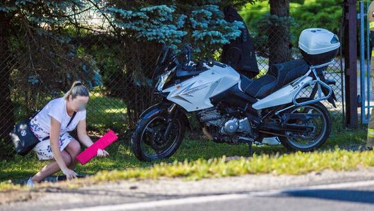 rozbity motocykl i kobieta która klęczy przy nim
