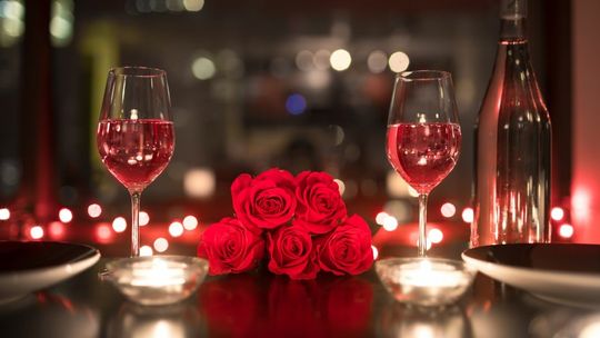 róże na stole w otoczeniu kieliszków z winem