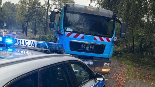 zdjęcie przedstawia policyjny radiowóz, za nim stoi samochód ciężarowy