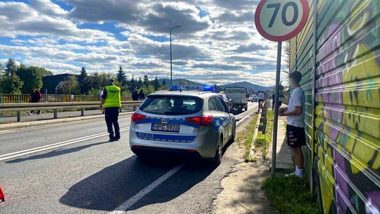 zdjęcie przedstawia policyjny radiowóz, obok policjant przechodzi przez jezdnię