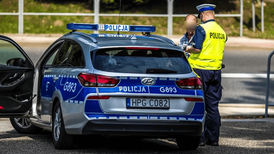 radiowóz policyjny, z prawej strony stoi policjant