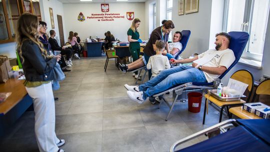 zdjęcie przedstawia salę na której siedzą mężczyźni na fotelach i oddają krew w PSP Gorlice, kobiety w fartuchach