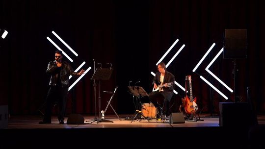 zdjęcie przedstawia muzyków na scenie, w tle ledy