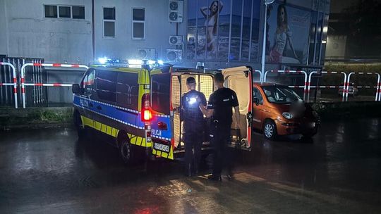 kogut na dachu policyjnego radiowozu, w tle policjant