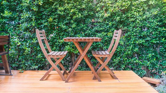 krzesła stojące przy stoliku na tarasie w ogrodzie w tle zielone rośliny na ścianie