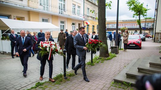 zdjęcie przedstawia mężczyzn w garniturach składających kwiaty przed tablicą upamiętniającą ks. Swieykowskiego