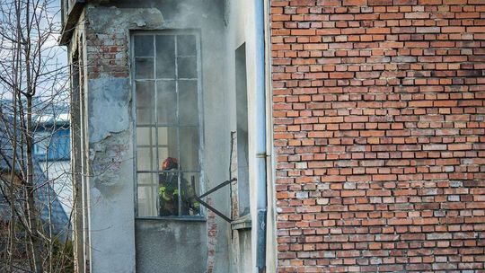 Strażak w aparacie powietrznym widziany w budynku przez okno