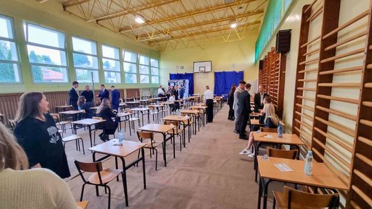 Matura 2025. Jedna piąta uczniów nie poradziła sobie z egzaminem dojrzałości zdjęcie przedstawia salę gimnastyczną w szkole na której stoją ławki, przy nich uczniowie