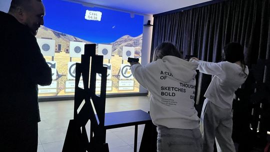 zdjęcie przedstawia ludzi w budynku strzelnicy