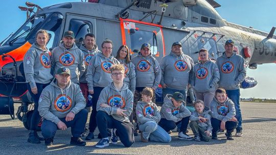 zdjęcie przedstawia grupę osób przed wojskowym helikopterem