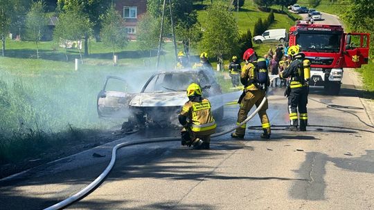 strażacy gaszący pojazd osobowy na ulicy