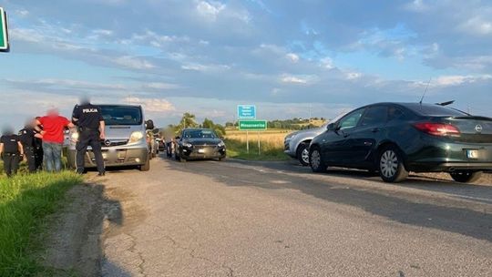 Zdjęcie przedstawia pojazdy i ludzi na jezdni