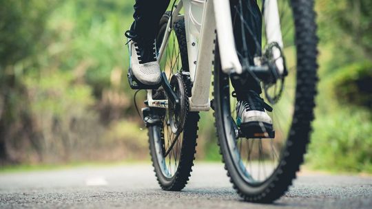 Na co zwrócić uwagę, kupując pierwszy rower crossowy? zdjęcie przedstawia osobę jadącą na rowerze po szutrowej drodze