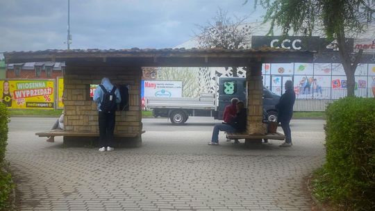 zdjęcie przedstawia przystanek autobusowy w gorlicach, na ławkach siedzi kilka osób