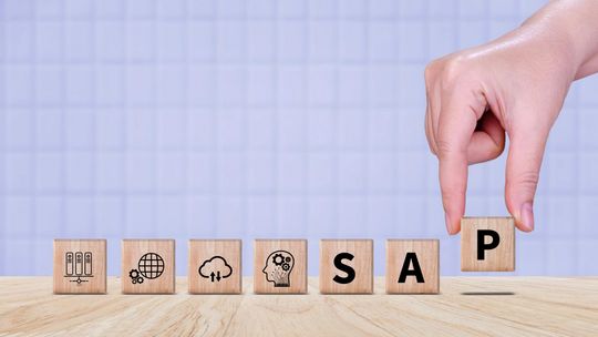 Nowa era cyfryzacji: Jak SAP S/4HANA Cloud rewolucjonizuje kluczowe obszary przedsiębiorstwa zdjęcie przedstawia klocki, które ktoś kładzie na biurko