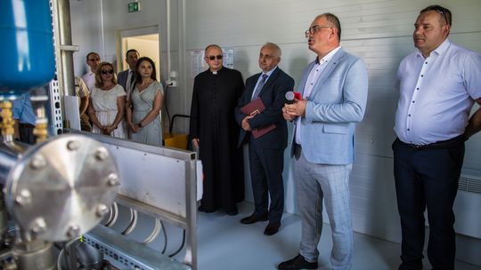 zdjęcie przedstawia kobiety i mężczyzn stojących w pomieszczeniu koło silników w przepompowni