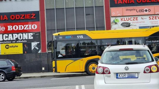 żółty autobus jadący ulicą miasta