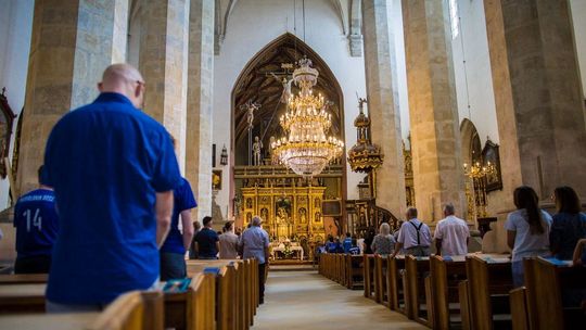 zdjęcie przedstawia wnętrze kościoła z ławkami i ołtarzem na pierwszym planie