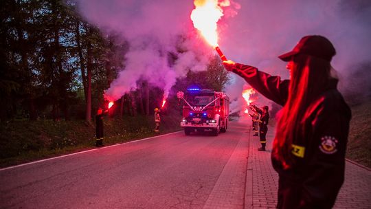 zdjęcie przedstawia samochód strażacki jadący ulicą podczas powitania wozu strażackiego w OSP Staszkówka