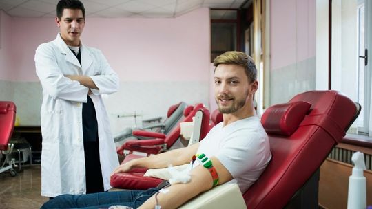 mężczyzna na fotelu oddaje krew, obok stoi lekarz