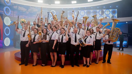 zdjęcie przedstawia grupę muzyków w mundurach trzymających instrumenty w górze