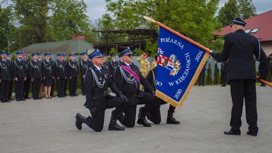 zdjęcie przedstawia strażaków klęczących przed sztandarem