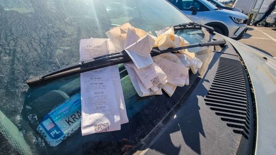 zdjęcie przedstawia samochód z blankietami za wycieraczką za parkowanie