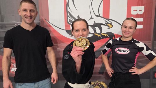 zdjęcie przedstawia dziewczynę pokazującą medal, obok inna dziewczyna w kimono, i mężczyzna