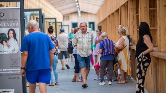 grupa osób chodzących pomiędzy stanowiskami pasażu Bieckiego Jarmarku Kultury