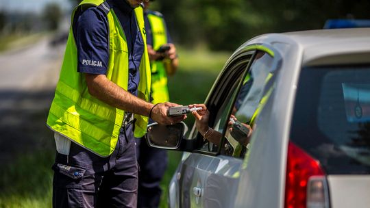 zdjęcie przedstawia policjanta podającego ustnik kierowcy