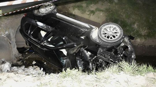 zdjęcie przedstawia samochód leżący na boku w rowie