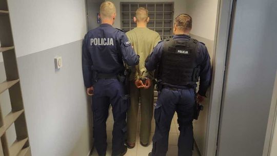 dwóch policjantów trzymających aresztanta