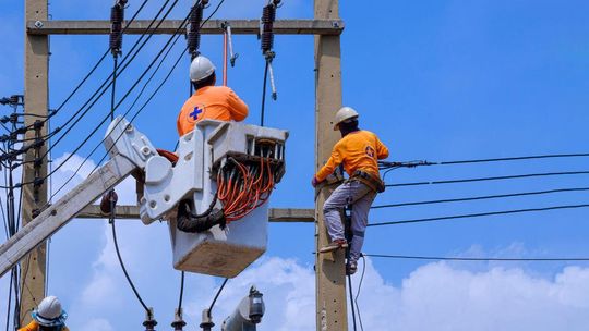 zdjęcie przedstawia robotników na słupie energetycznym