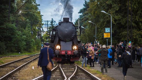 parowóz stojący na peronie wśród ludzi