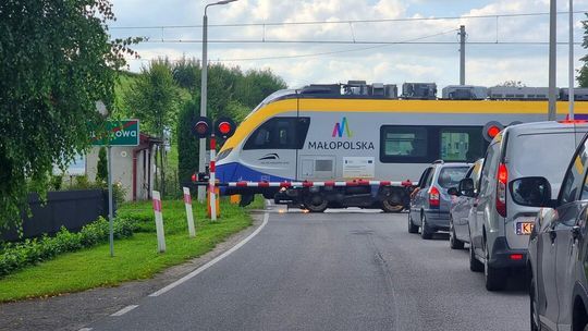 Zdjęcie przedstawia przejeżdżający pociąg przez przejazd kolejowy