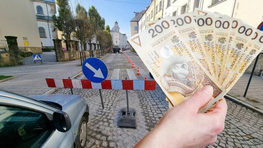 Ulica Wróblewskiego w Gorlicach, z boku wizerunek ręki trzymającej plik banknotów o nominale 200 złotych