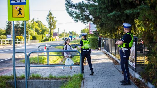 policjantka podaje ulotkę dziewczynce przy przejściu dla pieszych w Ropicy Polskiej