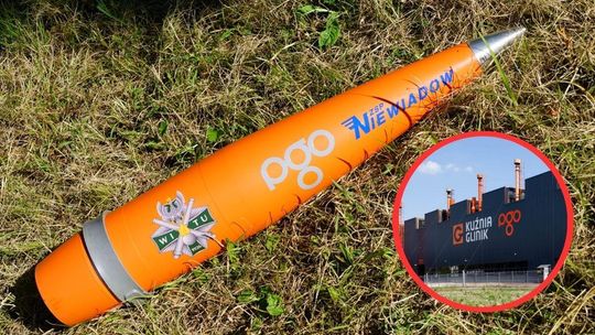 pomarańczowy pocisk leżący na trawie, obok budynek kuźni w gorlicach