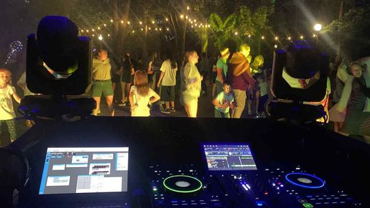 zdjęcie przedstawia tańczących ludzi w tle konsola dj-a