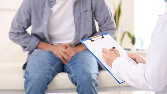 zdjęcie przedstawia mężczyznę siedzącego na leżance, przed nim lekarz z kartką i długopisem