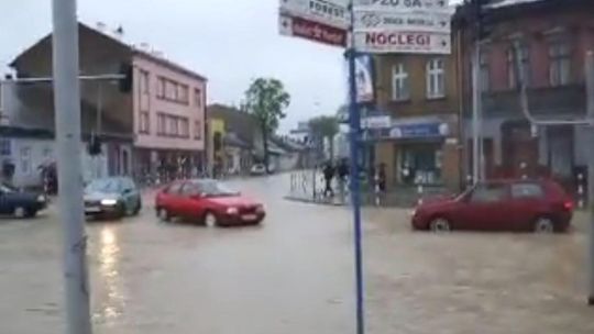 zdjęcie przedstawia zalaną ulicę po której jedzie samochód