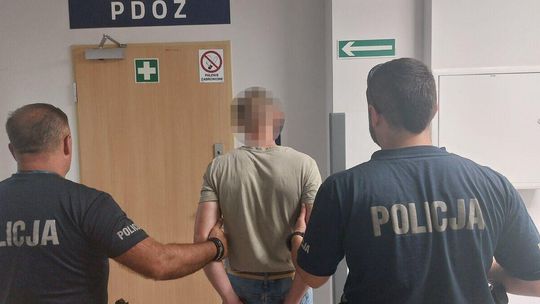 Zdjęcie przedstawia doprowadzenie mężczyzny do PDOZ przez dwóch funkcjonariuszy Policji