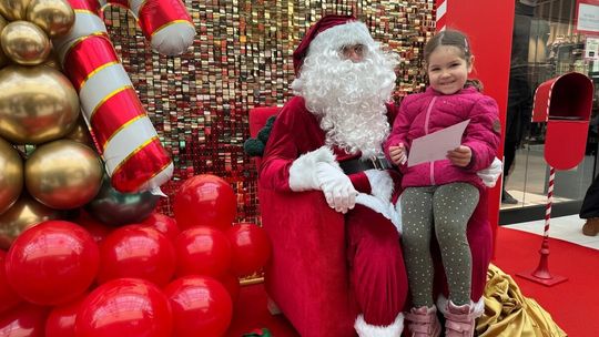 zdjęcie przedstawia św. Mikołaja z dzieckiem na kolanach