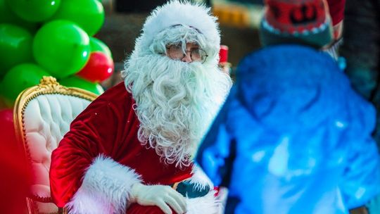 zdjęcie przedstawia św. Mikołaja z dzieckiem na kolanach